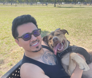 Samuel Martinez, owner of Trusty Tail, enjoying a sunny day at a Pearland park with his happy dog.